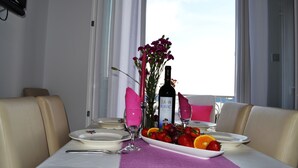 A dining table set with plates, cutlery, a bottle of ZLAAN PLAVAC wine, and a fruit platter.