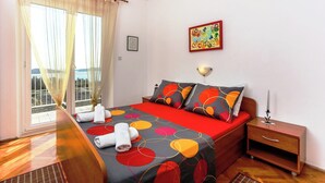 A hotel room with a bed, a nightstand, a lamp, and a view of the outdoors.