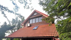 A house with a red-tiled roof, a covered patio with red chairs, and a green lawn. - Best of Ilidza Villa (Sarajevo)