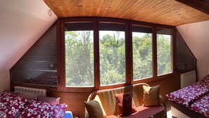 A bedroom with a sloped ceiling, large windows, a radiator, and a bed with floral bedding. - Best of Ilidza Villa (Sarajevo)