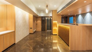 Un hall d’hôtel moderne avec des lambris en bois, un comptoir d’accueil et un sol en marbre.