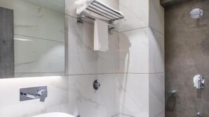 Une salle de bain moderne avec un grand miroir, un lavabo blanc, des toilettes et un espace douche.
