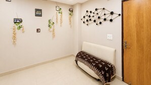 Une pièce dotée d’un ventilateur de plafond, d’un canapé, d’une porte et de décorations murales, notamment des photos encadrées et des plantes suspendues.