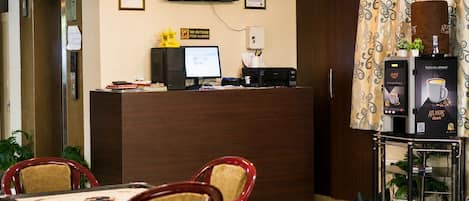 Bancada de recepção com monitor de computador, máquina de café e aviso indicando 'Não é permitido trazer alimentos de fora'.