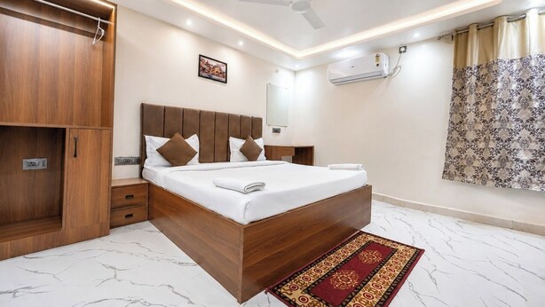 Une chambre à coucher moderne avec un lit en bois, un ventilateur de plafond, un climatiseur et un sol en marbre.