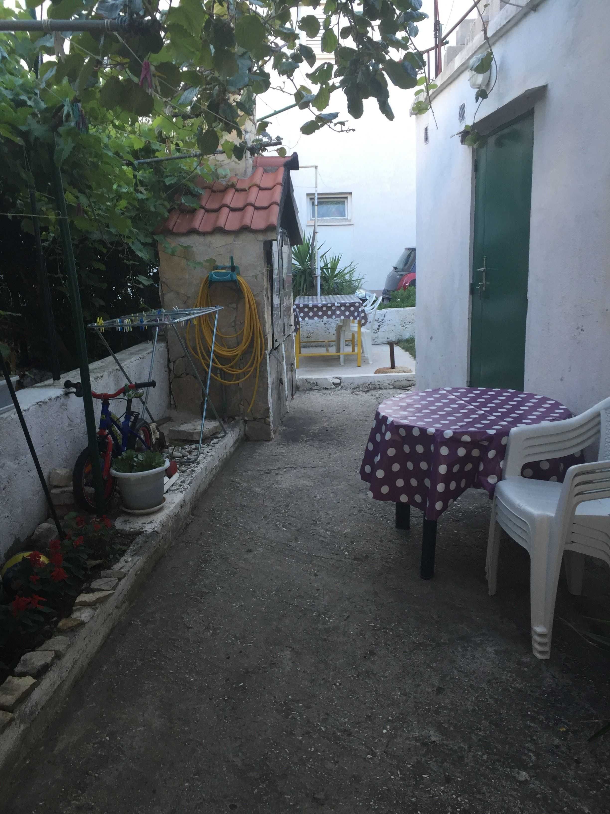 Un petit patio extérieur avec une table et des chaises, un vélo et un tuyau d’arrosage.