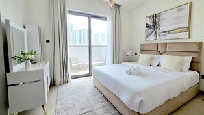 Een moderne hotelkamer met een groot bed, een bureau met een bloevas, een groot raam met gordijnen en uitzicht op de stad.