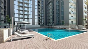 Een modern appartementencomplex met een zwembad op het dak, met meerdere balkons en een houten terras.
