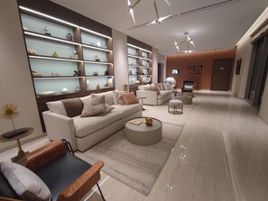 A modern living room with a sofa, coffee table, and shelves with decorative items. - Sobha Creek Vista Tower A Apartments (Dubai)