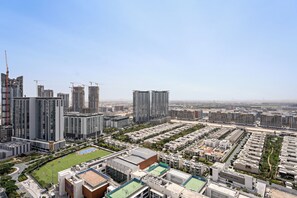 A high-rise residential building with multiple floors, a sports field, and surrounding modern buildings. - Sobha Creek Vista Tower A Apartments (Dubai)
