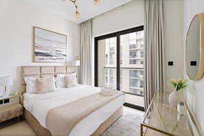 A modern hotel room with a large bed, a glass side table, a bedside lamp, a large window with curtains, and a view of the cityscape. - Sobha Creek Vista Tower A Apartments (Dubai)