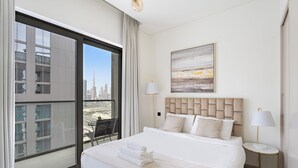 A hotel room with a large bed, two bedside lamps, a view of the cityscape, and a modern headboard. - Sobha Creek Vista Tower A Apartments (Dubai)