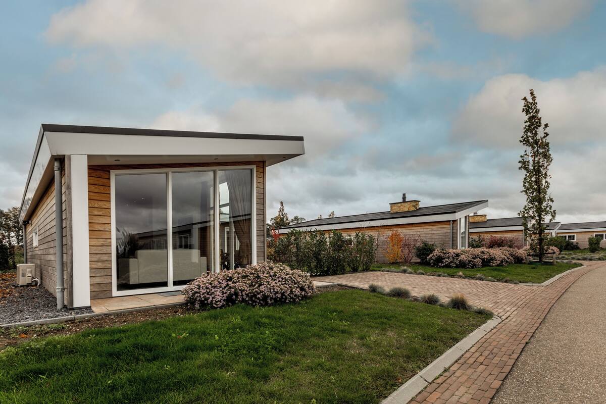 A modern house with a large sliding glass door, a brick pathway, and a well-maintained lawn.