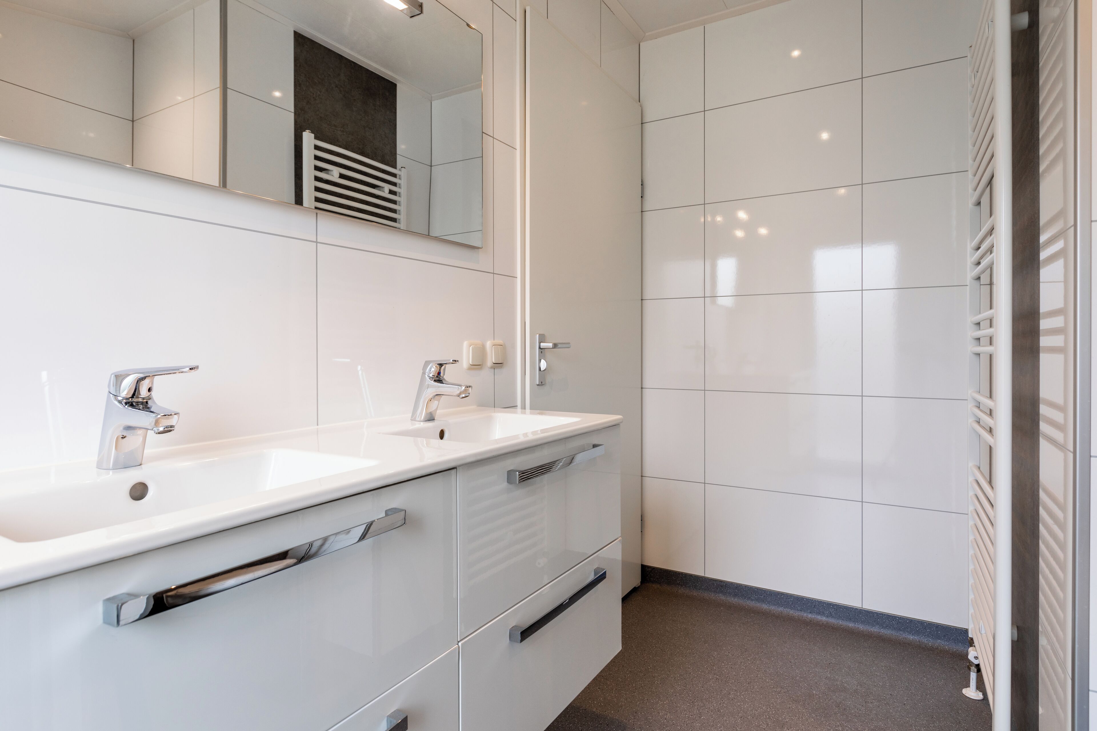 Un baño moderno con dos lavamanos, un espejo y una zona de ducha.