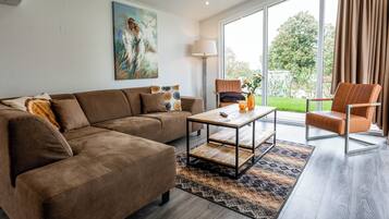 Een moderne woonkamer met een bruine bank, een houten salontafel en een bruine fauteuil.