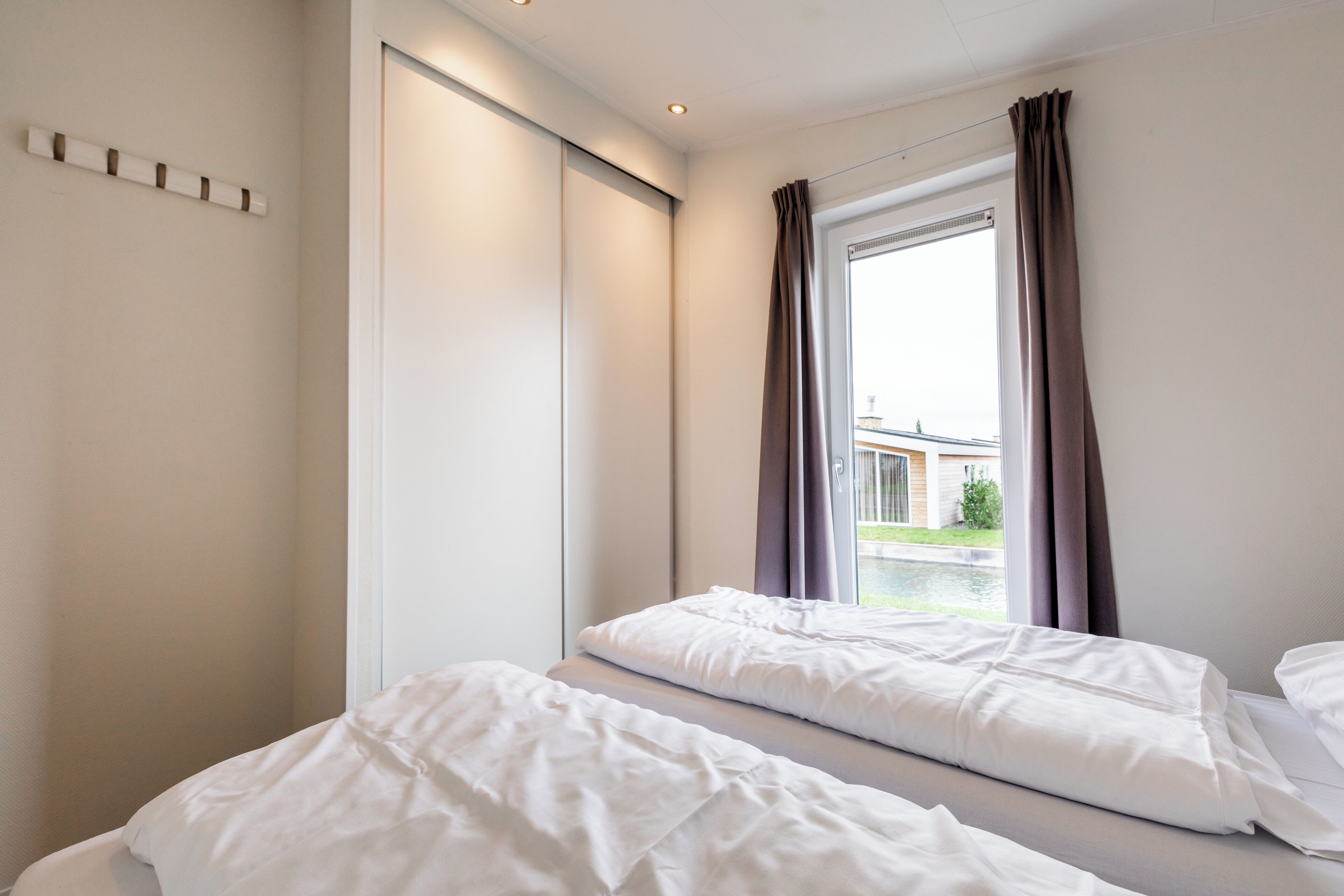 Habitación de hotel con dos camas, puerta corredera y ventana con cortinas.