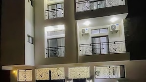 A multi-story building with balconies, air conditioning units, and decorative lighting. - Kapinga's house (Mbour)