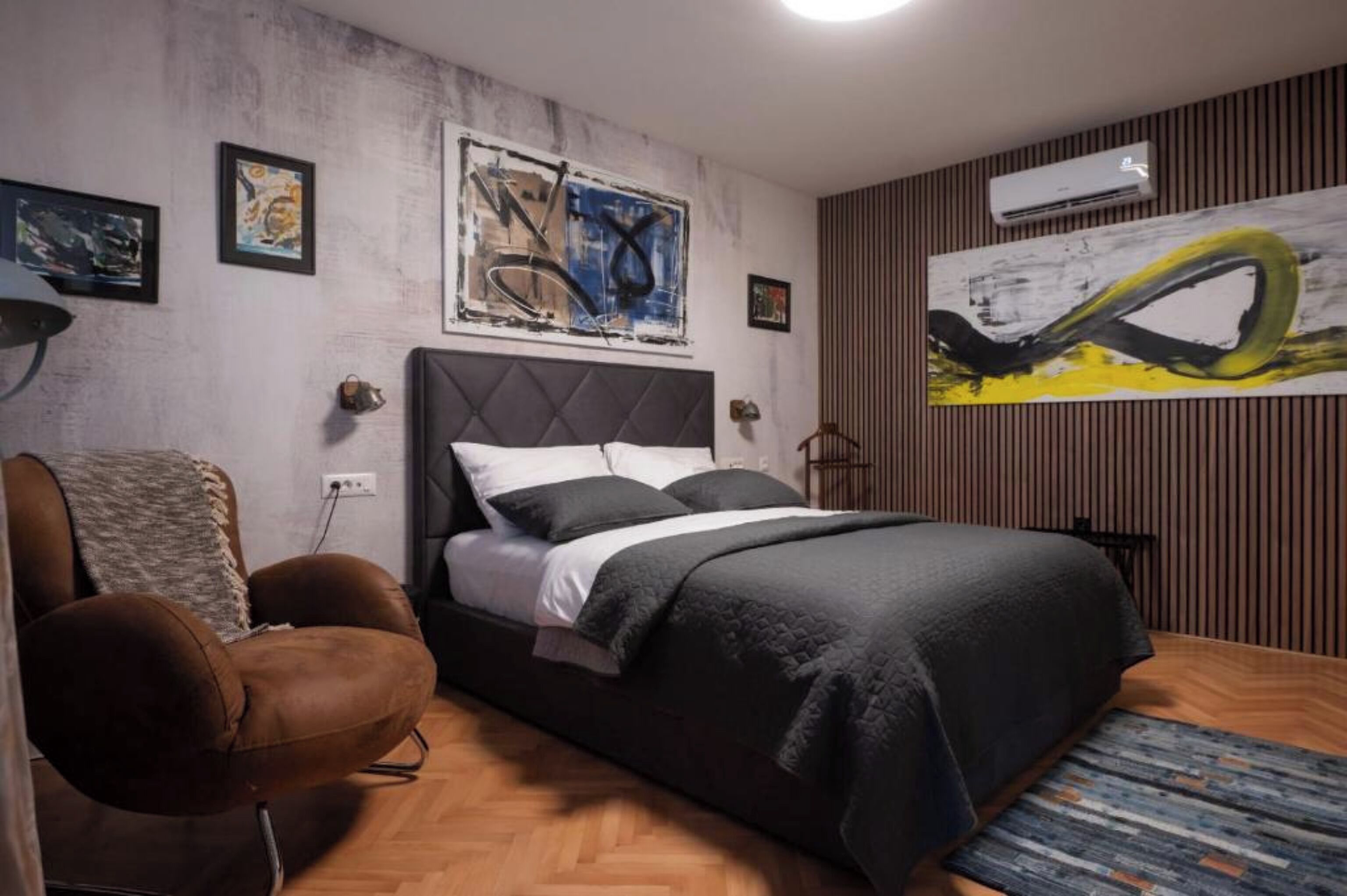 A bedroom with a bed, a chair, and artwork on the walls.