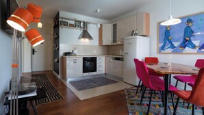 A compact kitchen with white cabinets, a refrigerator, and a dining area with a table and chairs.