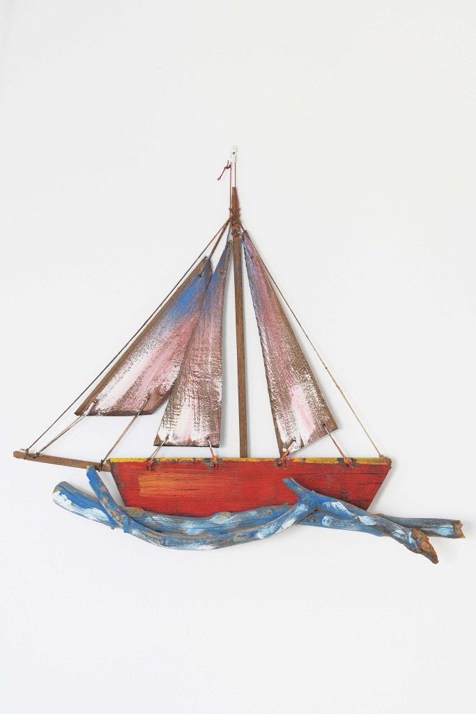 A model sailboat with a red hull and blue and red sails.