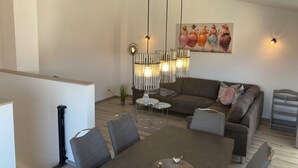 A modern living room with a dining area, a sofa, a coffee table, and a unique hanging light fixture. - "bijoux - Juwel" im Haus Meeresjuwel! (Dahme)