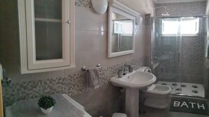 A bathroom with a glass shower enclosure, a sink, and a toilet.