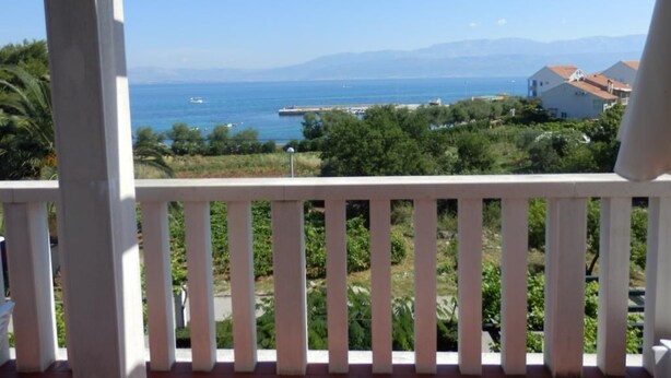A balcony with a view of the sea and distant mountains.