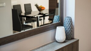 A modern dining area with a wooden table and chairs, a fruit bowl, and decorative vases on a wooden console. - Enjoy Summer from a lux flat steps to Sandy Beach (Maleme)