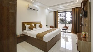 A modern hotel room with a large bed, a desk, a chair, and a balcony with curtains. - 360 Degree Hotel Medicity (Gurugram)
