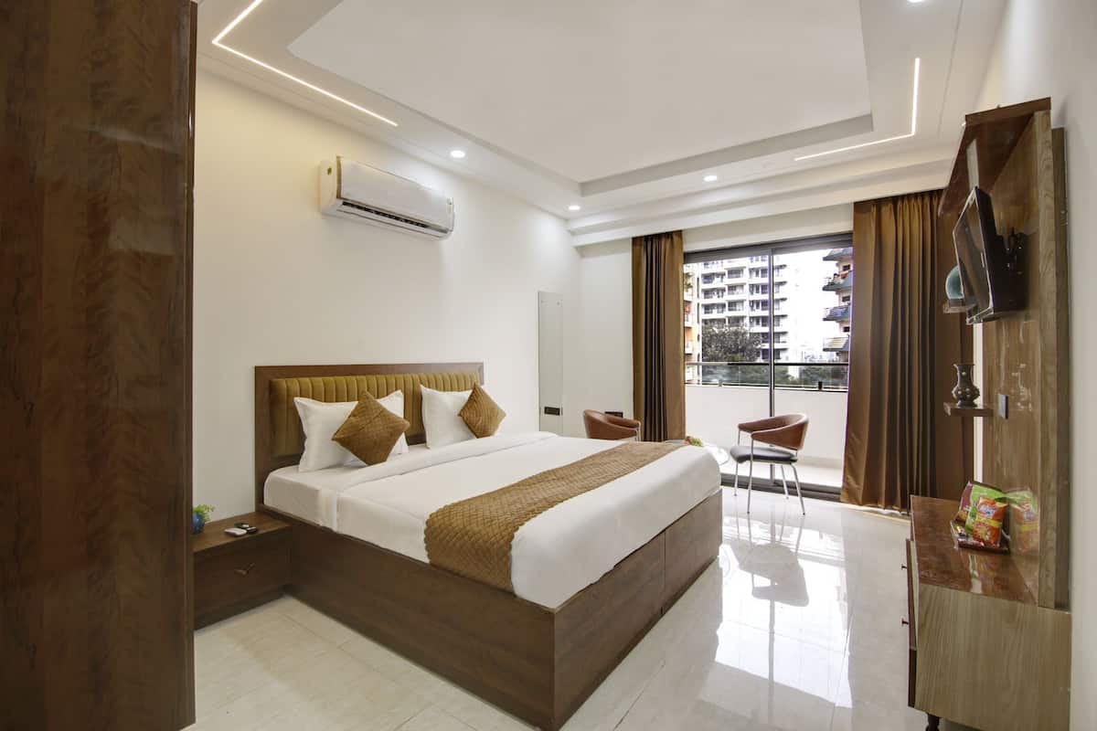 Quarto de hotel moderno com uma cama grande, uma escrivaninha, uma cadeira e uma varanda com cortinas.