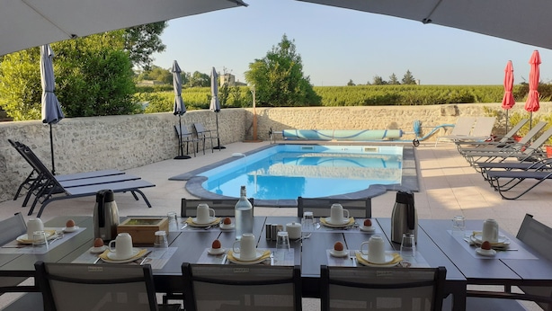 An outdoor pool area with lounge chairs and tables set up for dining. - Chambres d'hôtes "Au clocher" (Saint-Seurin-de-Cadourne)