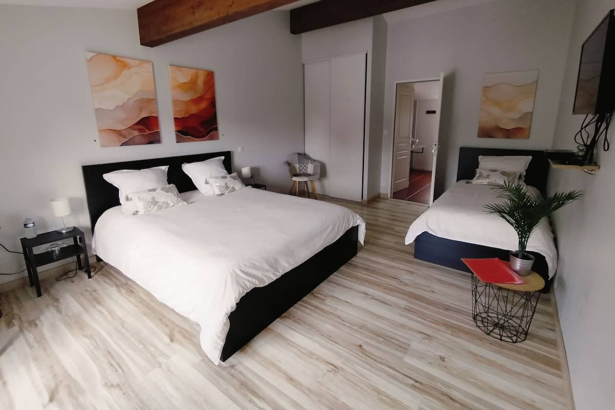 Ein modernes Hotelzimmer mit einem großen Bett, Nachttischen, einem Schreibtisch und einem Sessel.