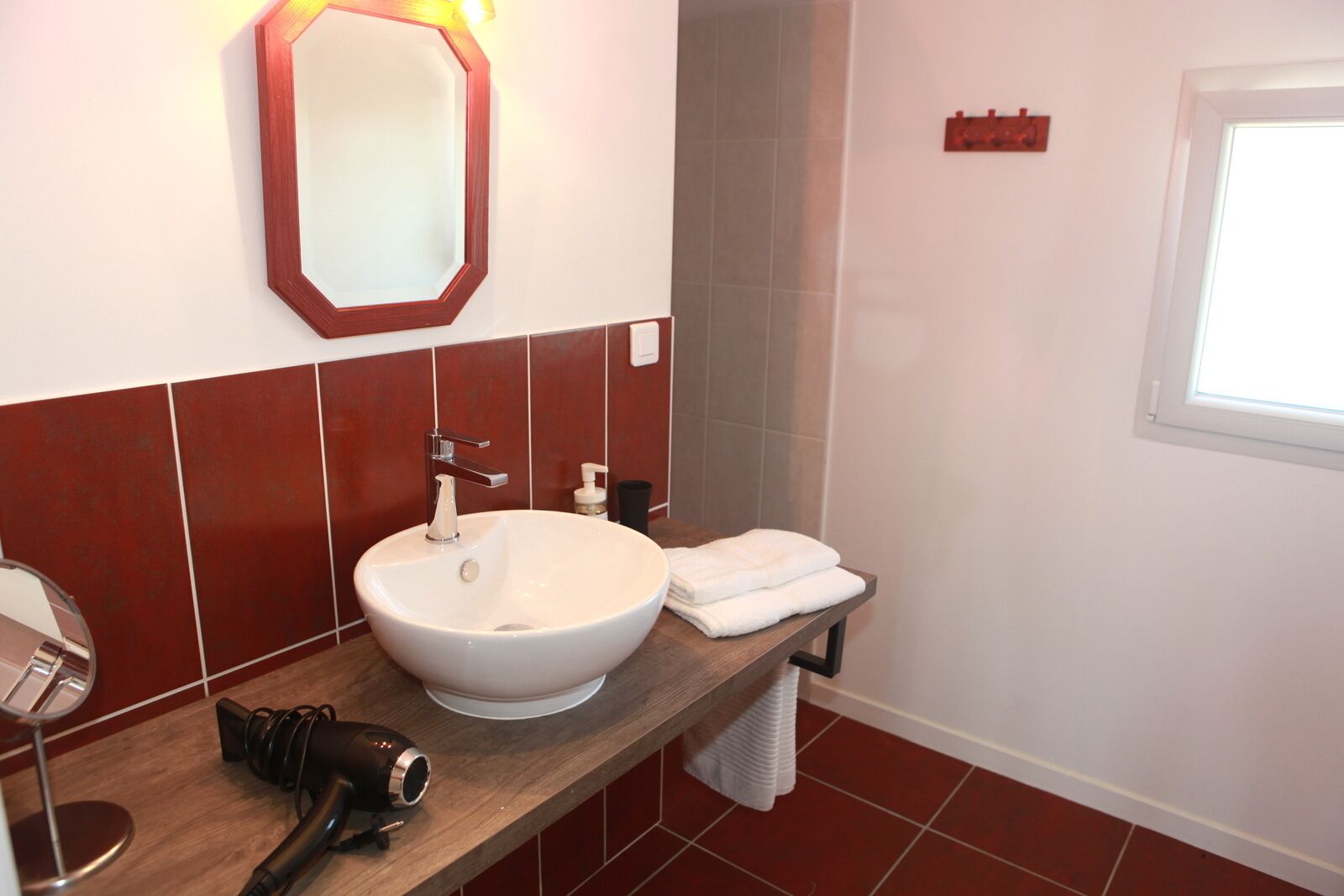 Un baño con un lavamanos blanco, un espejo, una toalla y un secador de pelo en la encimera.