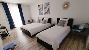 A hotel room with two beds, a desk, a chair, and artwork on the walls. - Chambres d'hôtes "Au clocher" (Saint-Seurin-de-Cadourne)