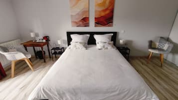 Ein Hotelzimmer mit einem großen Bett, zwei Nachttischen, einem Sessel und abstrakten Wandbildern.