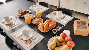 A breakfast table with croissants, fruit, juice, and coffee cups. - Chambres d'hôtes "Au clocher" (Saint-Seurin-de-Cadourne)
