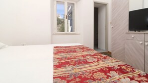 A bedroom with a bed, a window, a wardrobe, and a television.