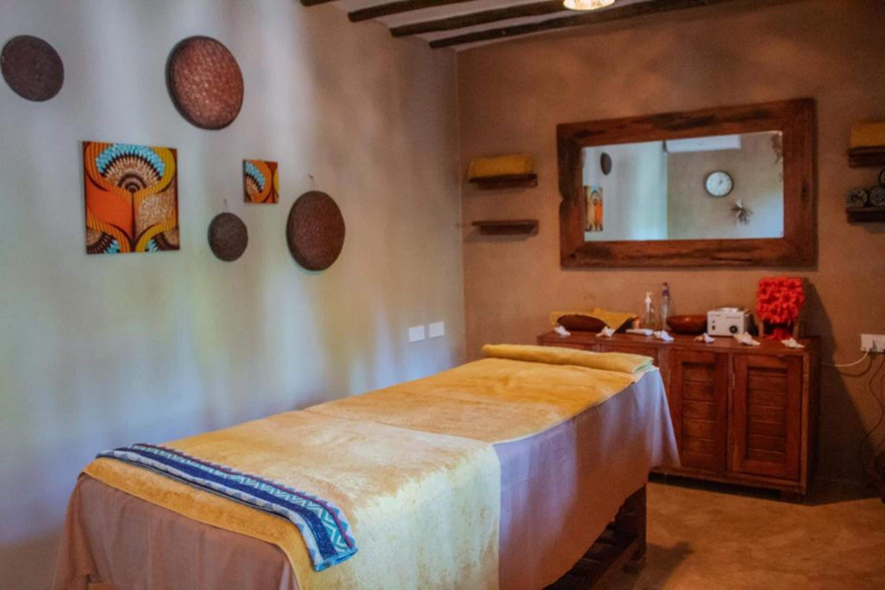 Une pièce comprenant une table de massage, un meuble en bois et des œuvres d’art décoratives accrochées au mur.