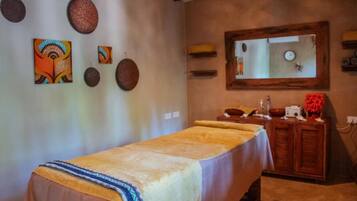 Une pièce comprenant une table de massage, un meuble en bois et des œuvres d’art décoratives accrochées au mur.