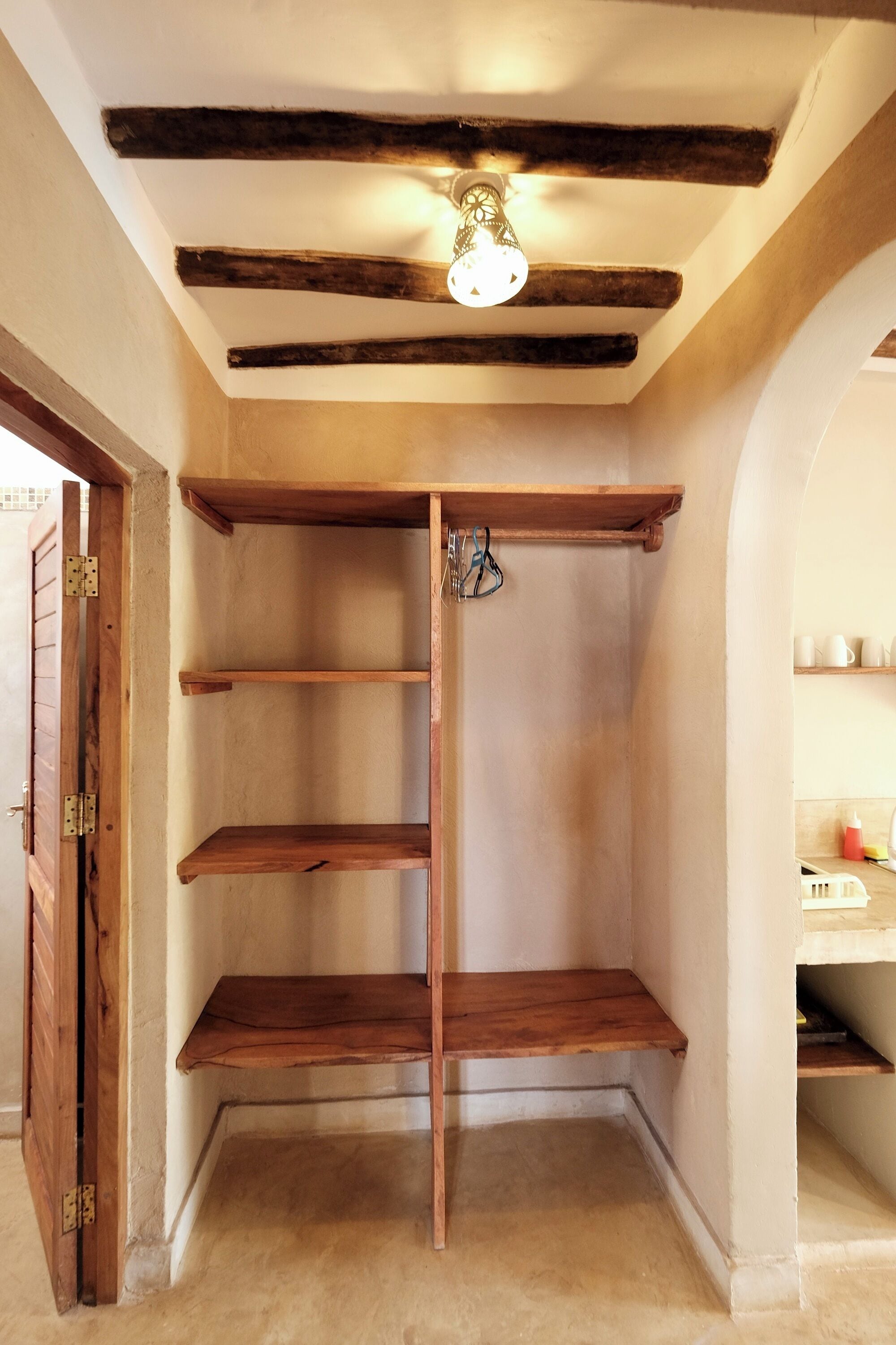 Un garde-manger d’angle avec des étagères en bois et un luminaire suspendu.