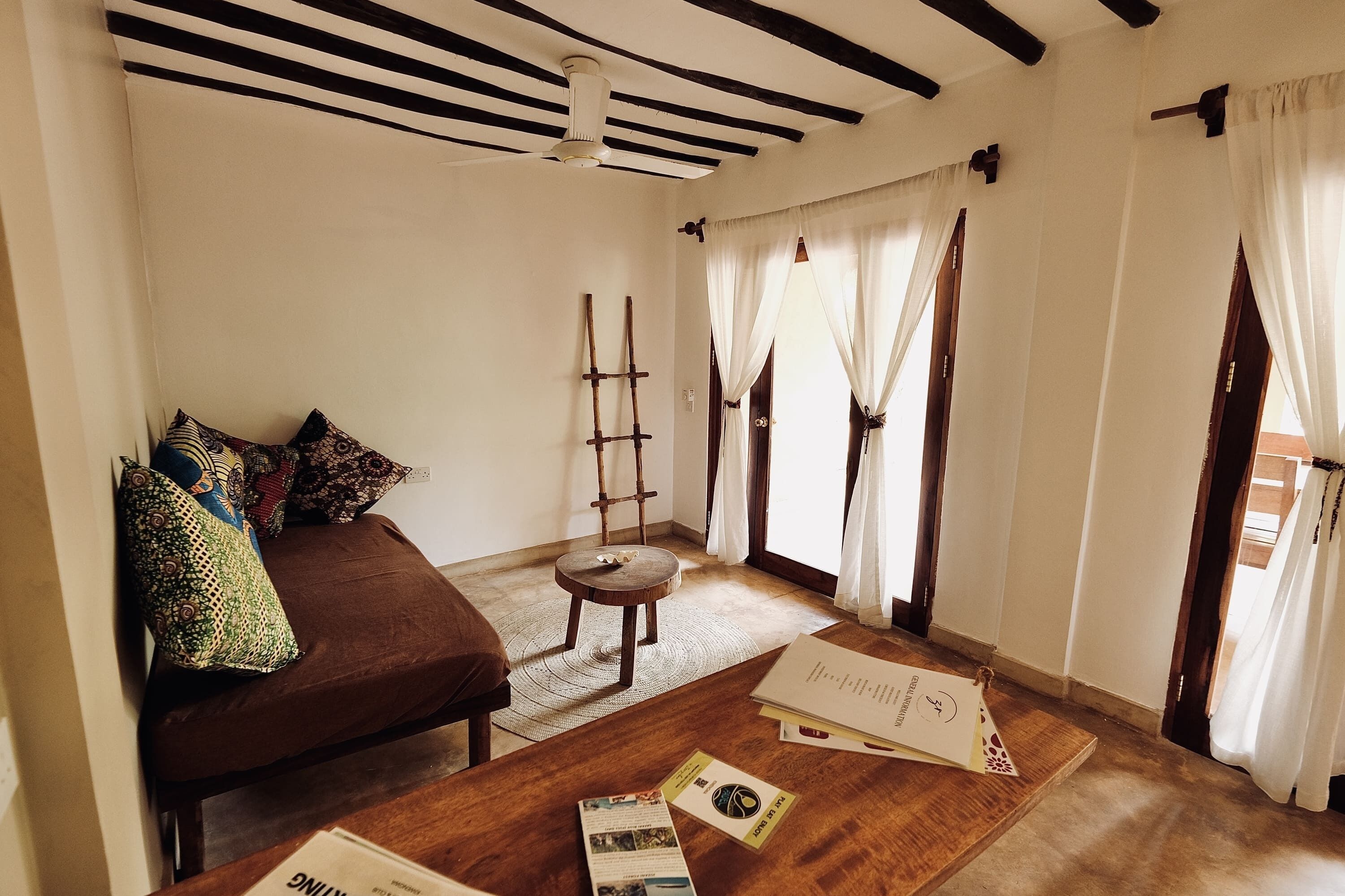 Ein gemütliches Zimmer mit einer braunen Couch, einem Holztisch mit Broschüren und einer Wandleiter.