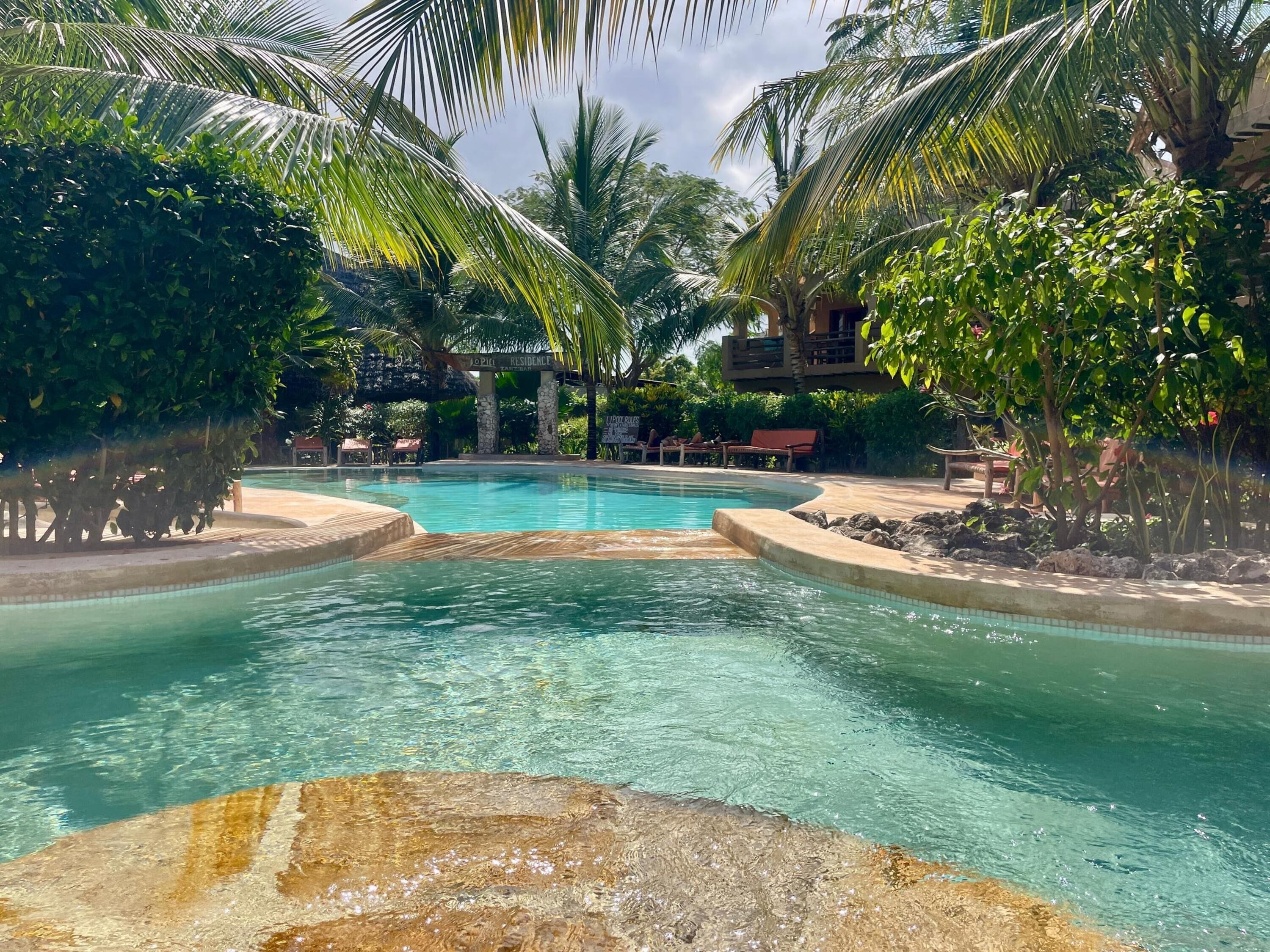 Una piscina rodeada de palmeras y un letrero que dice "RESIDENCE".