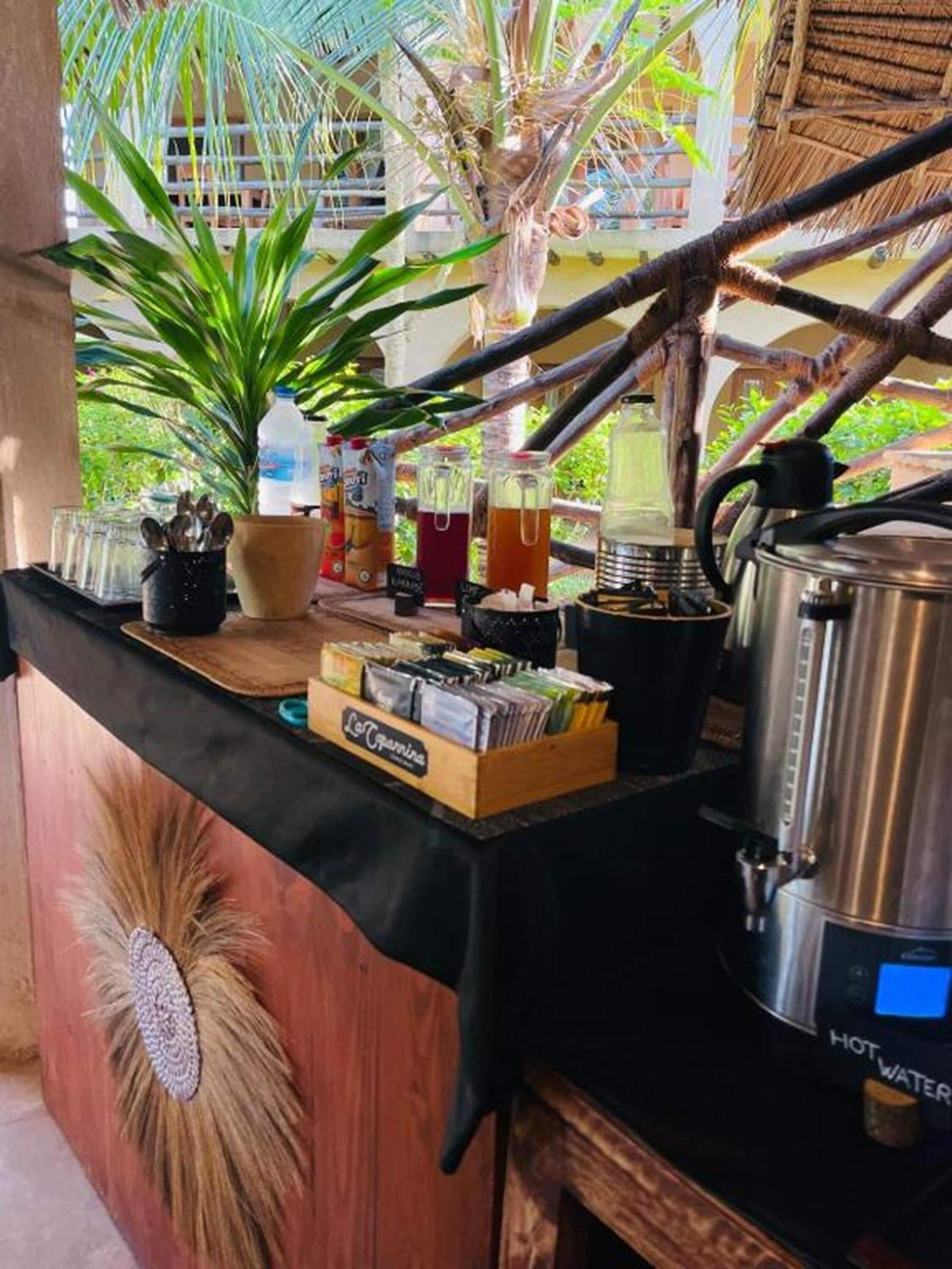 A buffet setup with a variety of food items, a hot water dispenser, and a coffee machine.