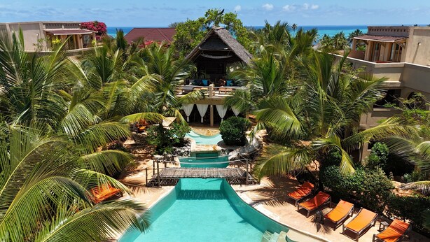 A resort with a central pool, palm trees, and a view of the ocean. - LaPili Residence (Kiwengwa)