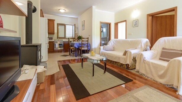 A living room with a TV, sofa, and a dining area with a table and chairs. - Apartment Petar (Konavle)
