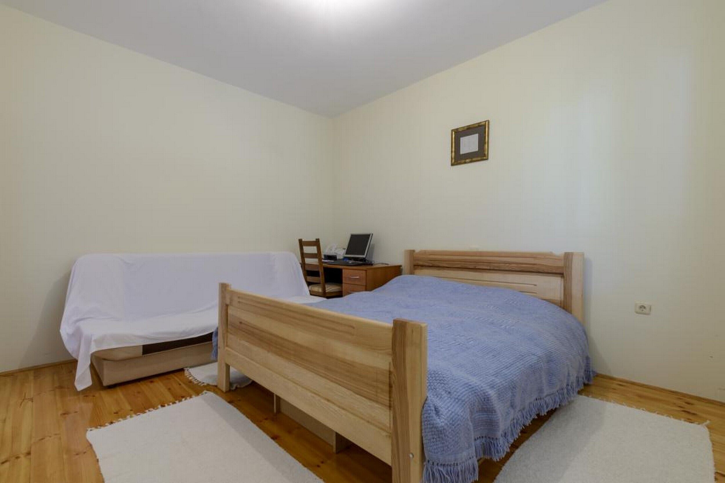 Una habitación pequeña con una cama individual, una mesita de noche con una computadora portátil, un escritorio pequeño y una silla.