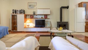 A compact living room with a television, speakers, a fireplace, and a small dining table. - Apartment Petar (Konavle)