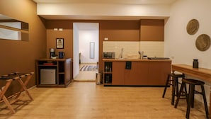Eine kompakte Küche mit einer zentralen Kochinsel, Holzbarhocker und einem kleinen Kühlschrank.