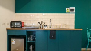 A compact kitchen with teal cabinetry, a built-in toaster, a mini-fridge, and a sink. - w* | Spacious 1BR in Plaza de Armas w/ Balcony (Cusco)