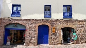 A building with a stone facade, blue doors, and windows with blue railings. - w* | Spacious 1BR in Plaza de Armas w/ Balcony (Cusco)